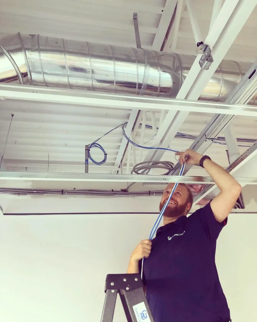 Employee of Running Cables installing data cable and ethernet cables in the ceiling of a commercial property.